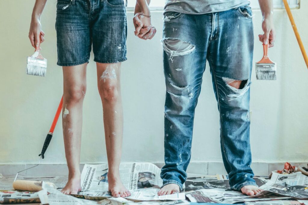 
One man and one woman are painting walls to renovate their home.