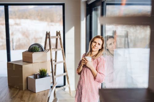 
A woman is looking outside through the windows of her house.