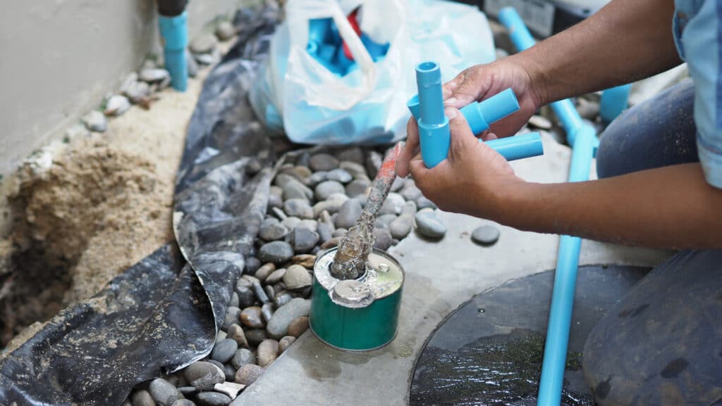 A drainlayer fixes a leaking underground pipe.