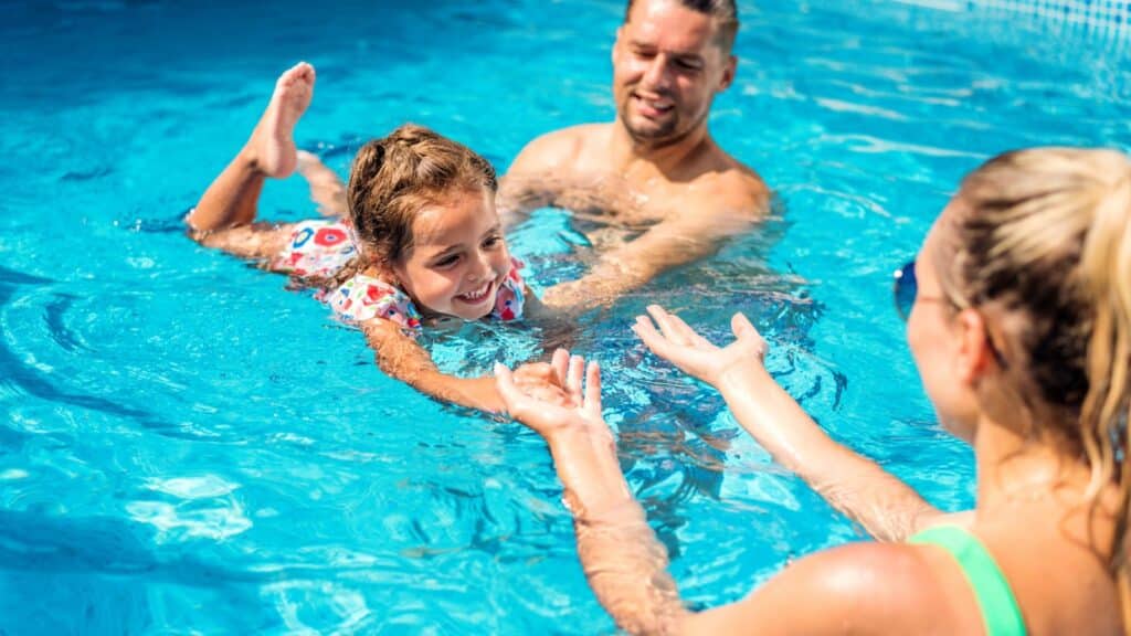 Parents teaching child to swim in a swimming pool