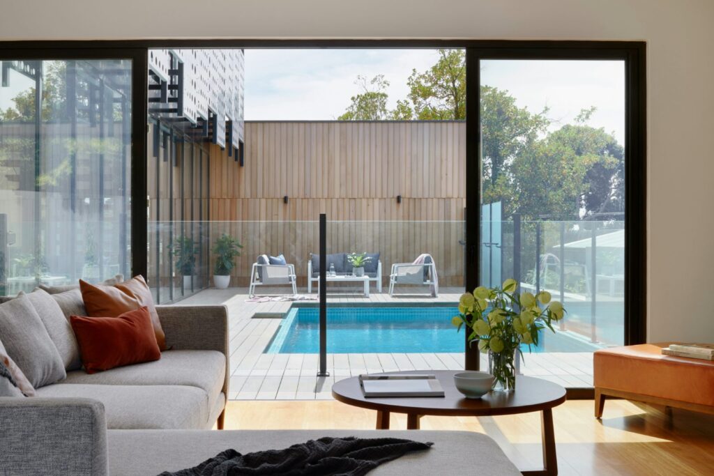 Stylish living room looking out to pool surrounded by glass pool fence