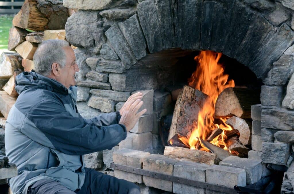 man warming himself by outdoor fireplace