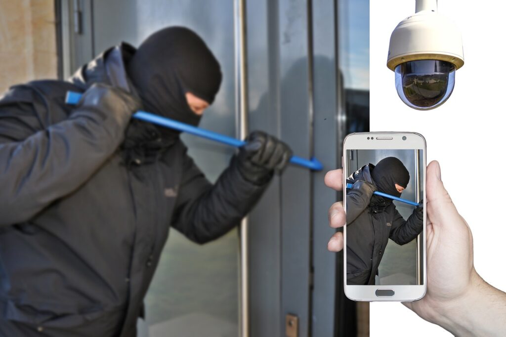 a man breaking into a home with a blue crowbar next to a camera and a hand holding a smartphone
