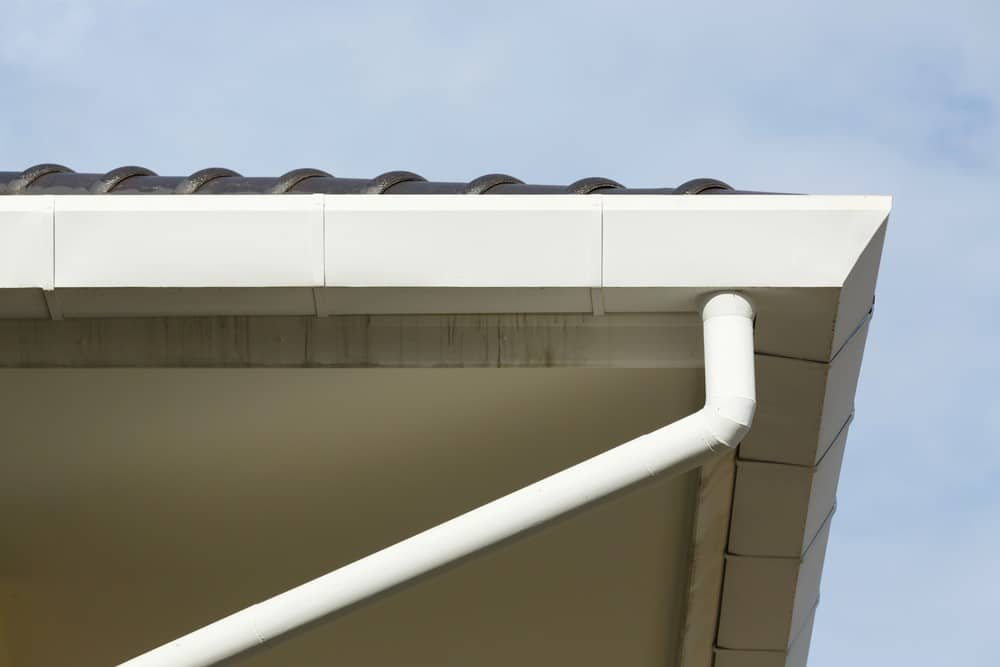 A continuous spouting system on a home roof showing clean fascia and downpipe for effective rainwater drainage.