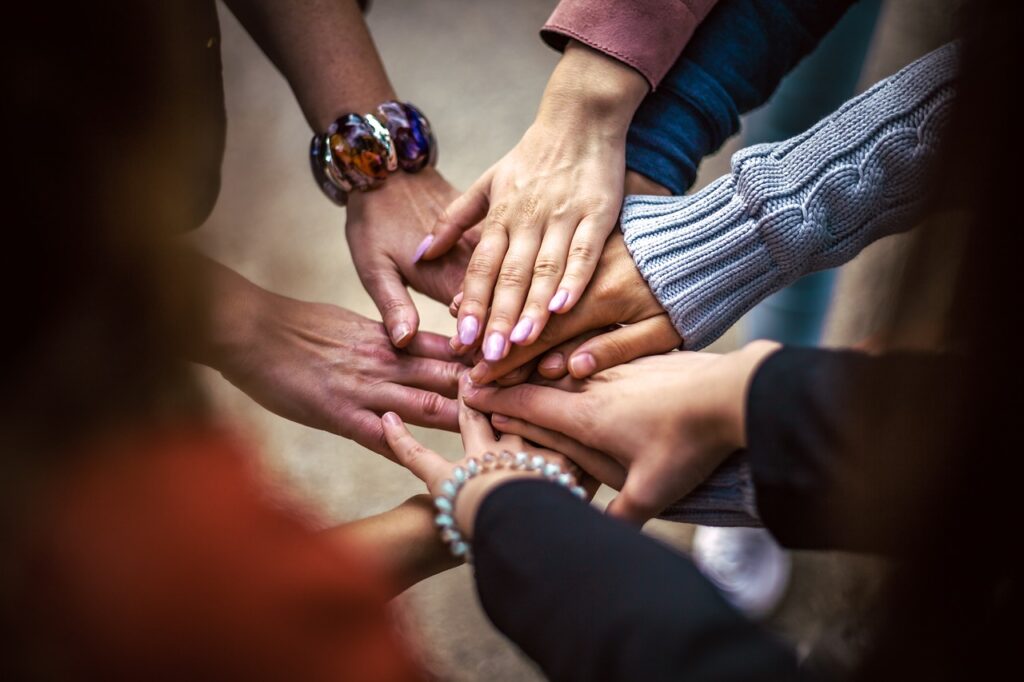 A ring of hands coming together in a circle for community protection. 